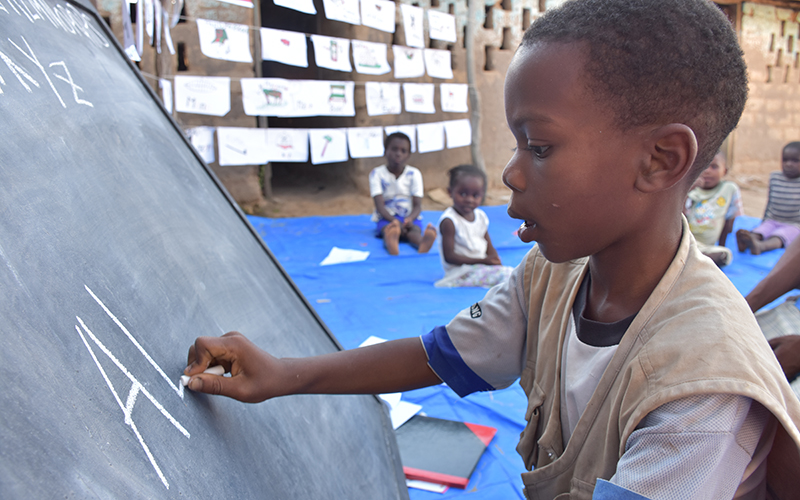 In the Democratic Republic of Congo, a young boy writes on a chalkboard.