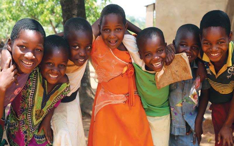 Seven children from Malawi embrace each other and smile.