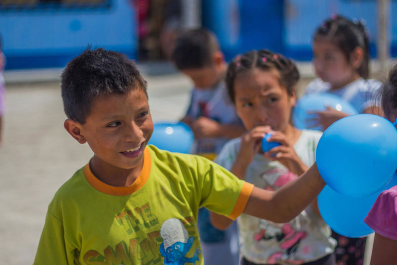 A boy from Peru plays with blue balloons.