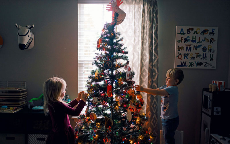 A boy and a girl decorate a Christmas tree together