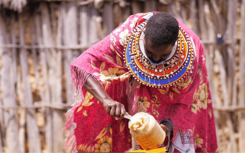A woman in a bright dress scoops honey into a container.
