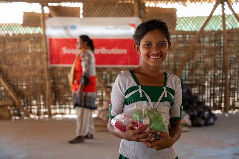 A Rohingya refugee girl holding a plastic bag with soap bars.