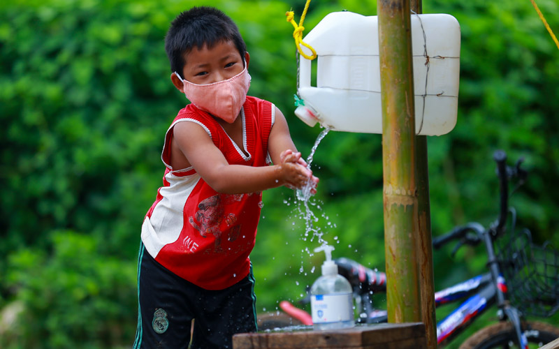 A young boy in Myanmar washes his hands using a tippytap