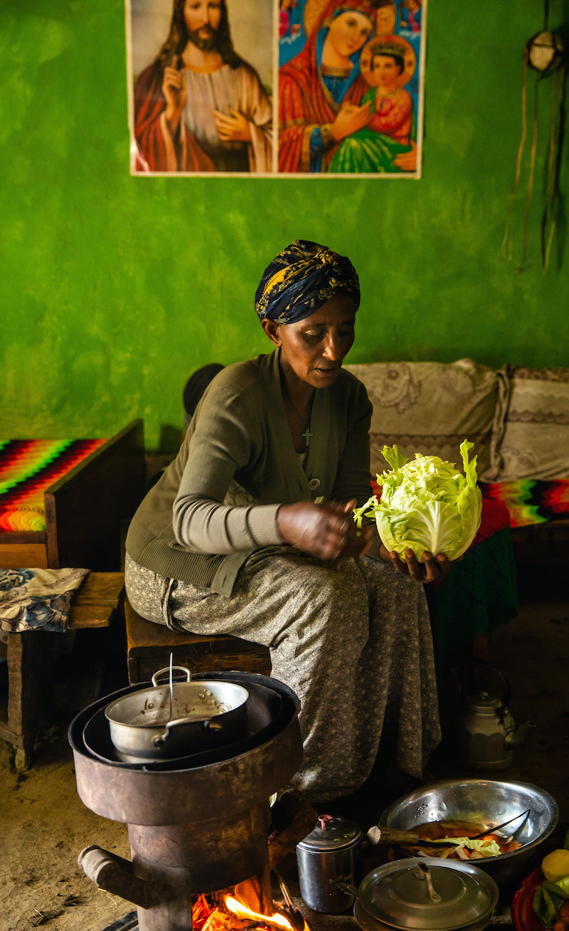 A woman breaks apart a head of lettuce in a bright kitchen