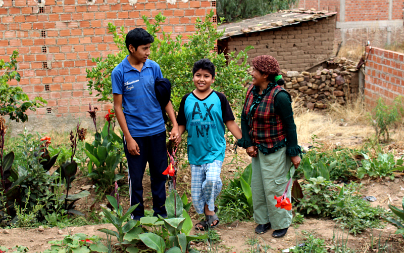 A mother and her two sons hold hands in a garden in Bolivia