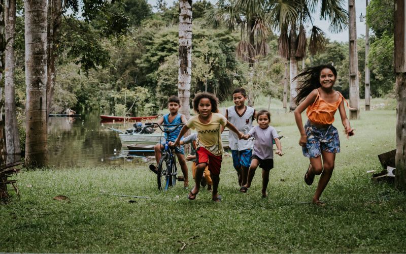 In Brazil, a group of children run to greet the World Vision Hospital Boat. The children are smiling broadly.