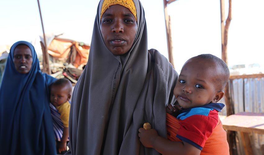 A mom holds her baby son on her hip in Somalia.