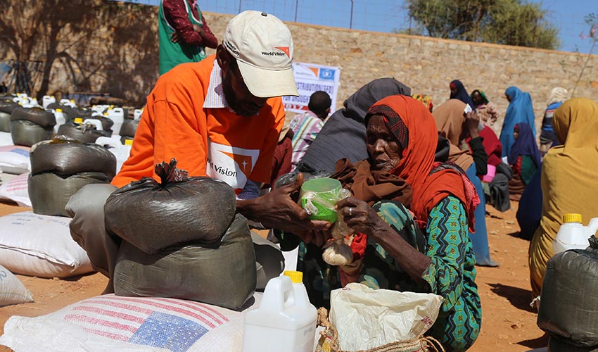 A World Vision humanitarian worker hands emergency items to a woman at a relief distribution in Somalia.