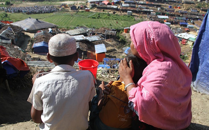 A woman with two little boys high on a hill, looking down at a community below.