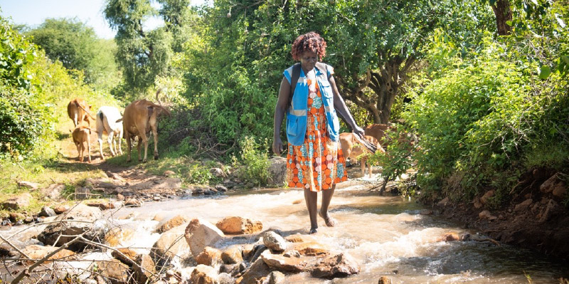 Florence crosses a river on her way to work as a community health advisor 