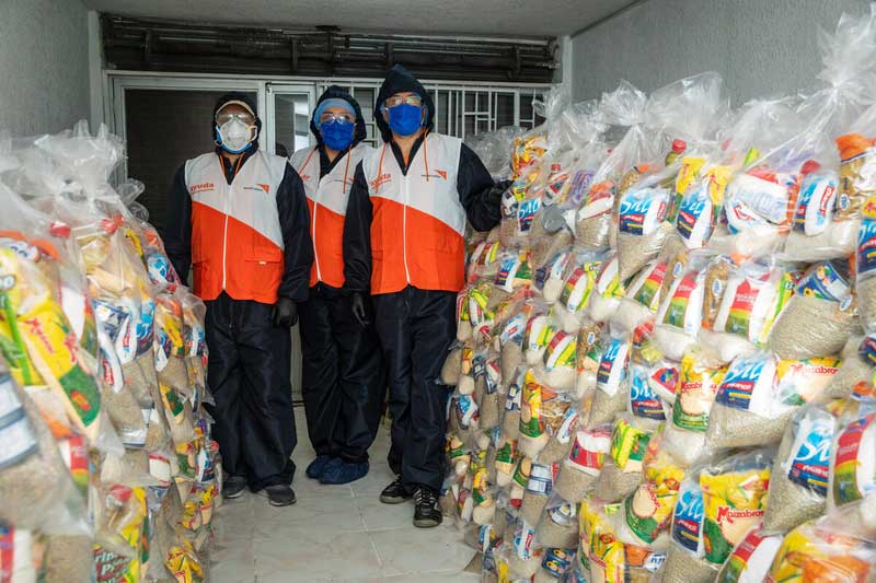 Three World Vision staff members in protective masks and gloves present thousands of care kits ready to be distributed in Ecuadorian communities.