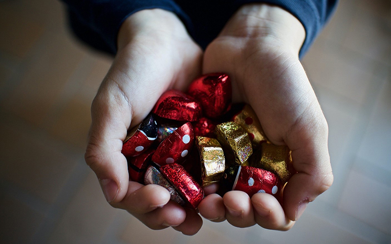 A person holds a bunch of wrapped chocolates in their cupped hands.