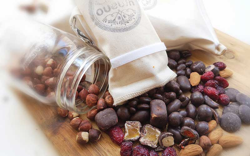 Chocolate-coated candies, almonds and dried fruits laid out on a wooden serving board.
