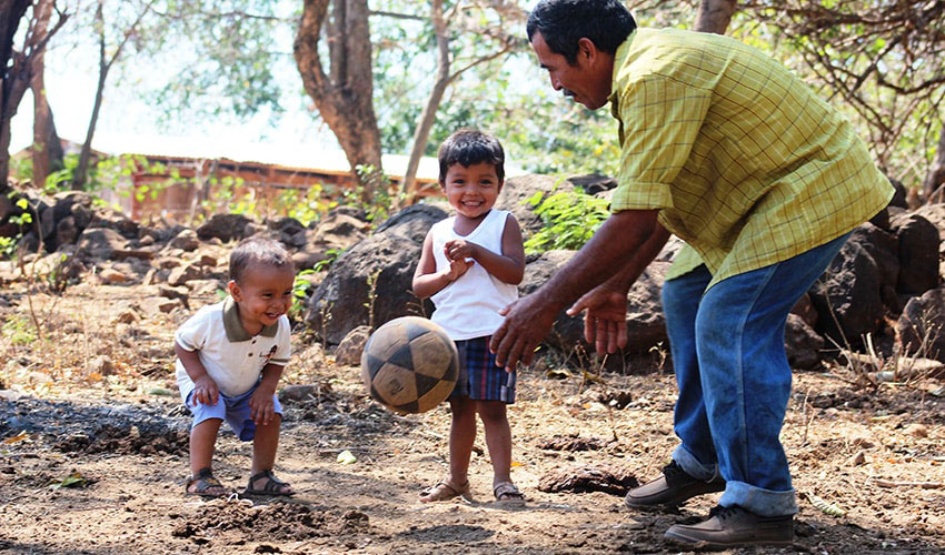 In El Salvador, a dad plays soccer with his two toddler age sons