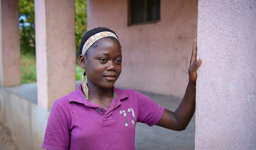 a teenage zimbabwean girl stands and looks off in the distance