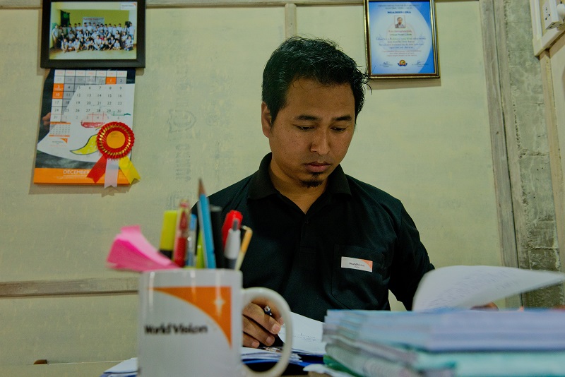 A humanitarian works at a desk with a World Vision mug on it.