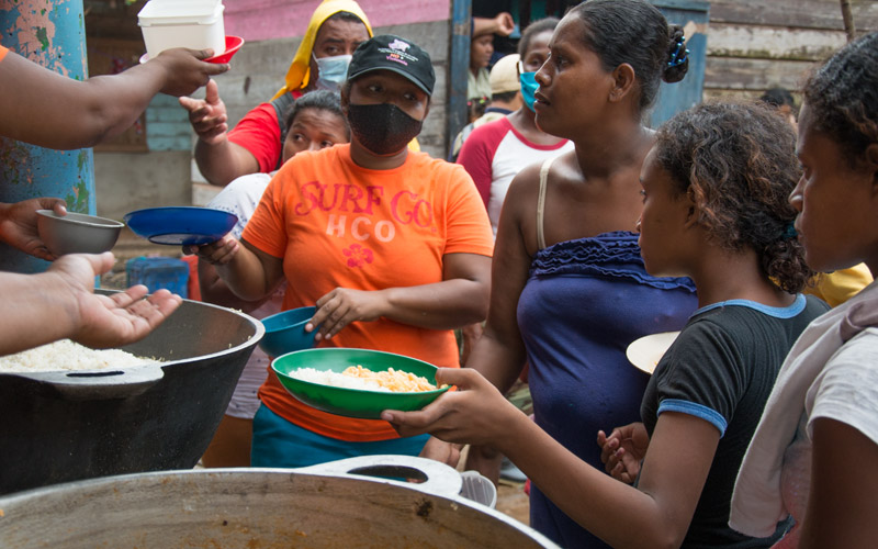 women and girls from Nicaragua line up at a community kitchen to receive food.