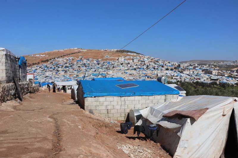 Temporary shelters are clustered close together on a hillside in Syria.