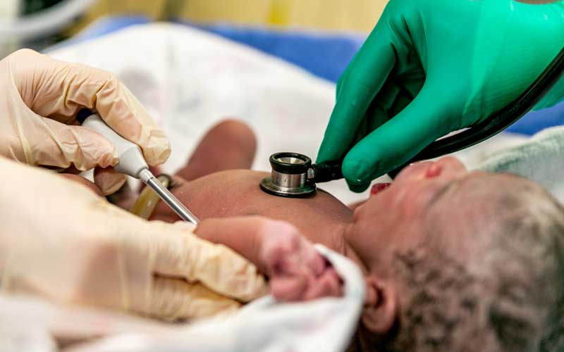 A newborn baby has their vitals checked. 