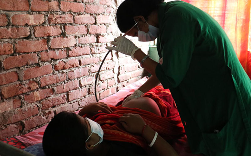 A health care worker checking the belly of a pregnant woman during a pre-natal care visit.