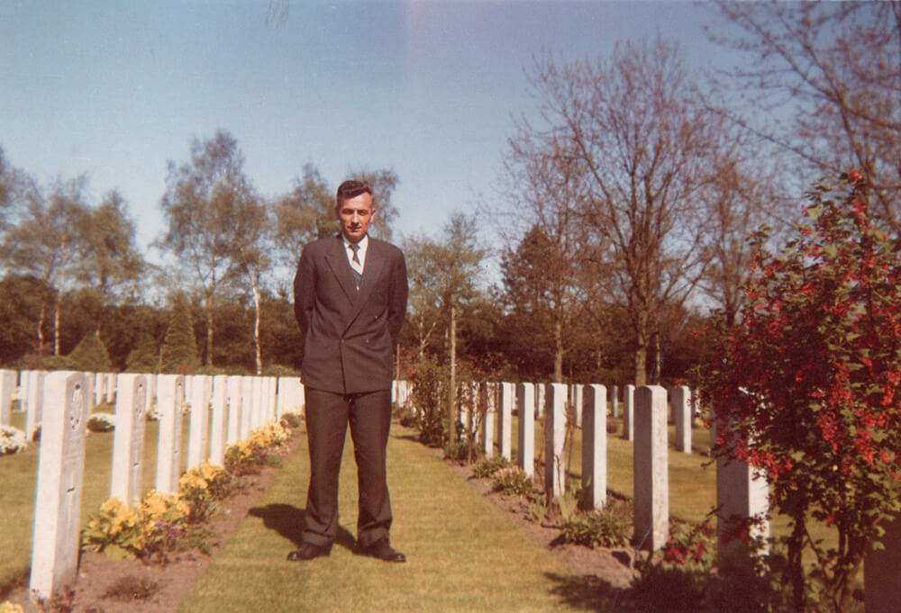 Arie Kamp standing Groesbeek Canadian War Cemetery in the Netherlands, wearing a black suit