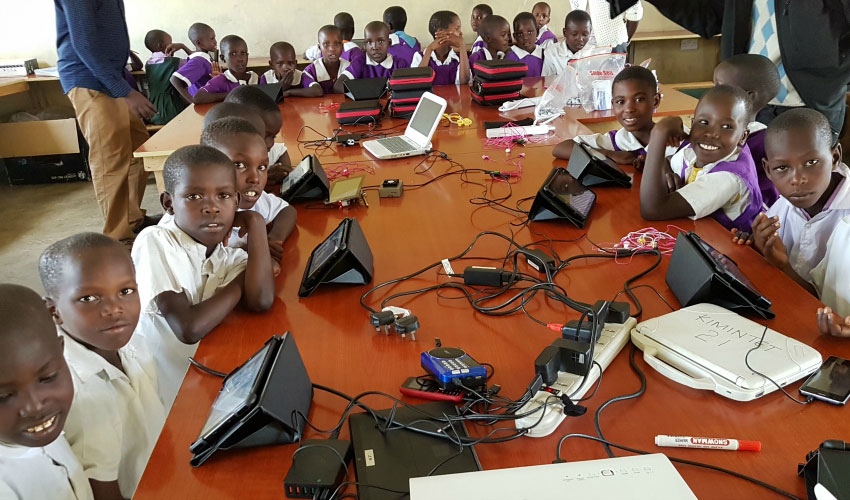 A grade one class in Kenya sit with tablets around a long table