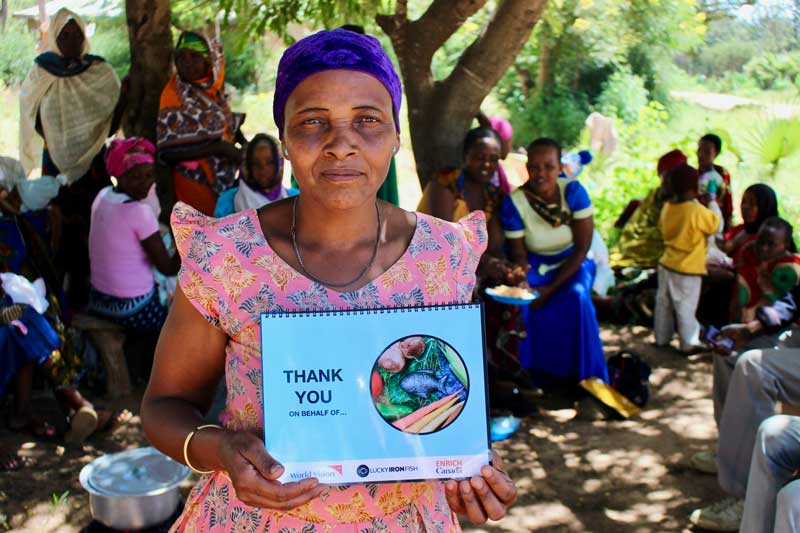 A woman in Tanzania holds a training manual provided by World Vision on how to use the Lucky Iron Fish