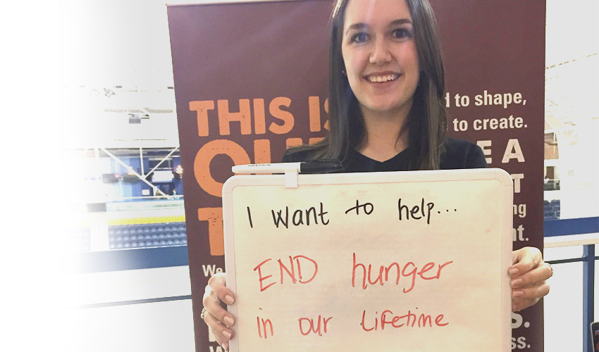Young woman holds sign that says I want to help...end hunger in our lifetime.