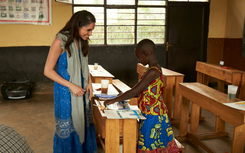Meghan Markle assists a little girl in Rwanda with her painting.
