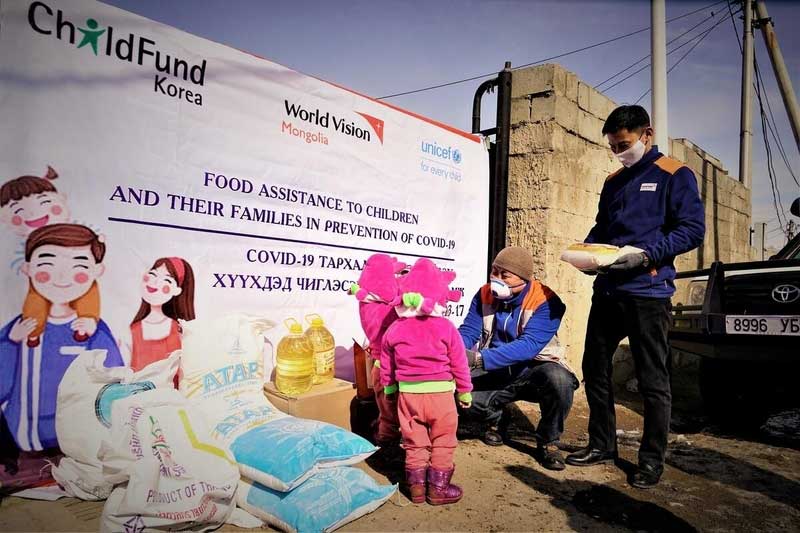 World Vision staffers wearing masks distribute food and hygiene assistance packages to children in Mongolia.
