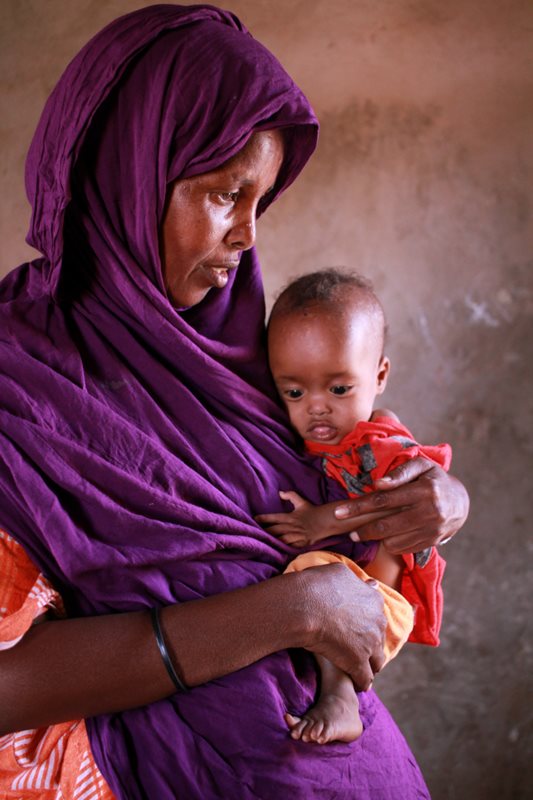 A mother in a purple head-scarf holds her child