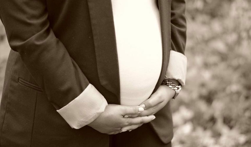 Close up of pregnant belly of woman in dark blazer.