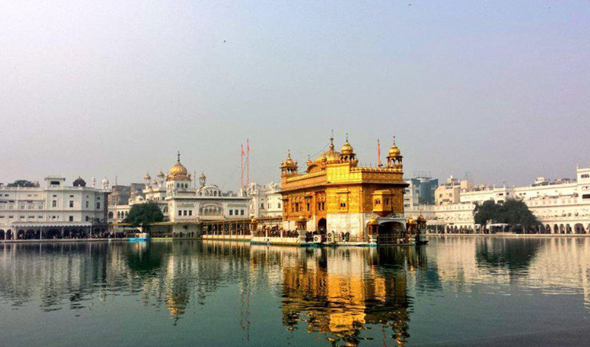 Elaborate golden structure jutting out over water with white buildings in background.