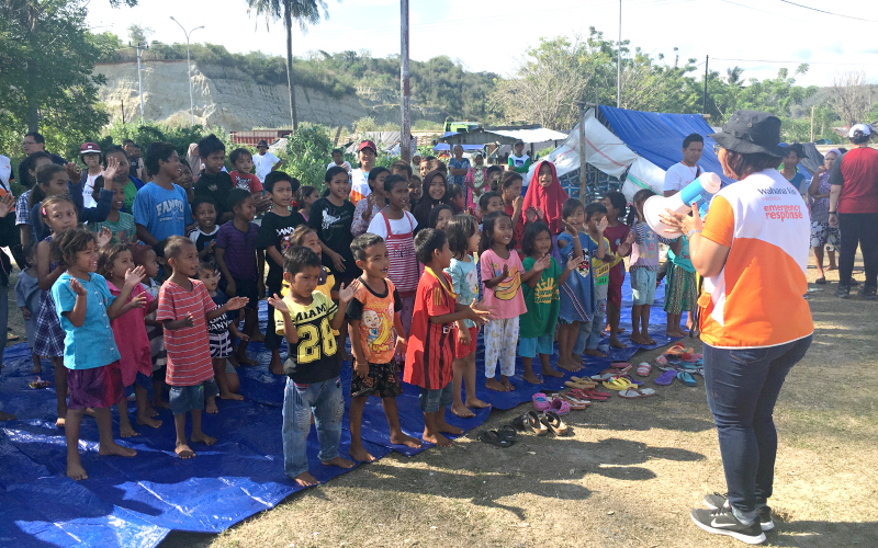A World Vision staff member leads a group of children in song.