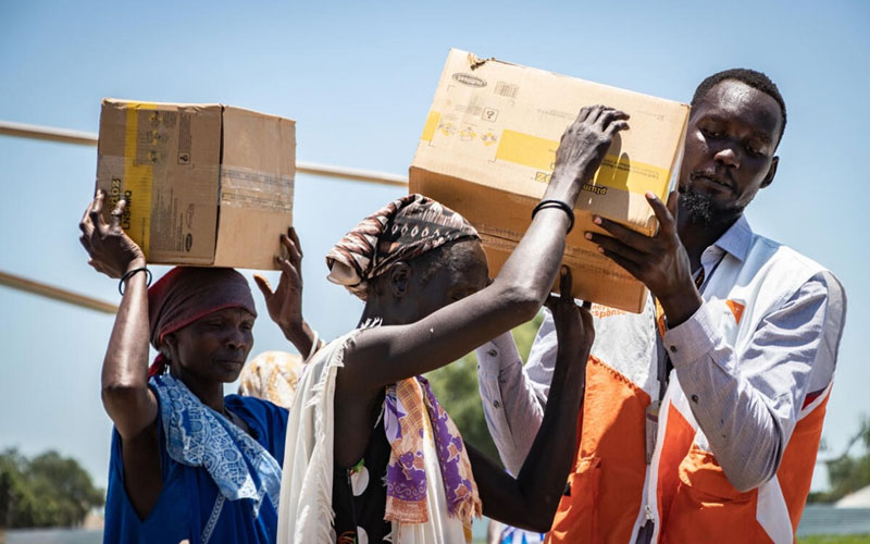 In South Sudan, two women receive boxes of food rations from a World Vision worker.