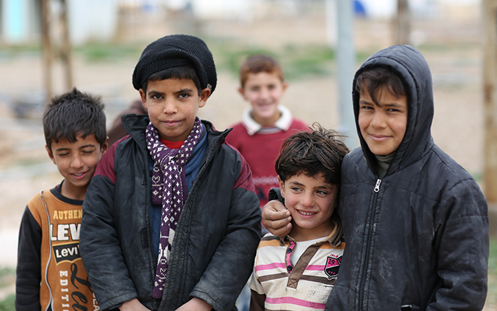 Four Iraqi boys stand side by side. Two of them look at the camera.