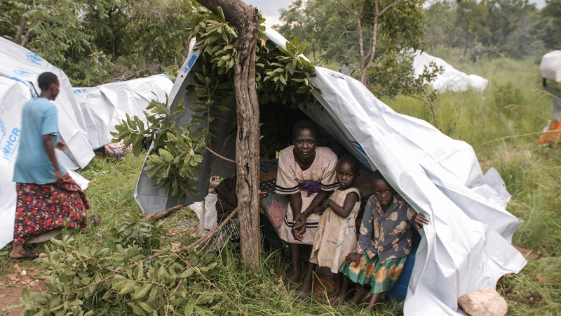 A mother and her two children take shelter under their tent in a refugee camp in South Sudan.