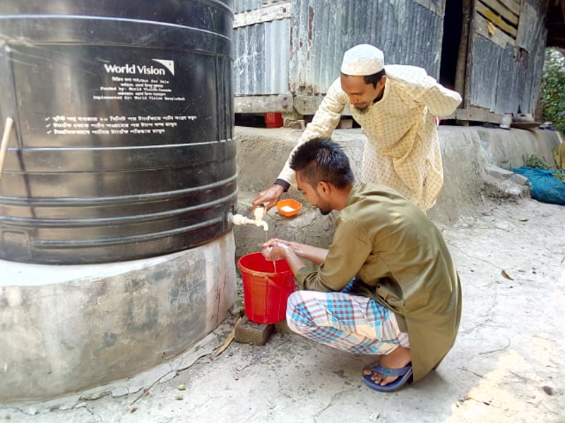 A faith leader from Bangladesh helps a community member wash his hands.