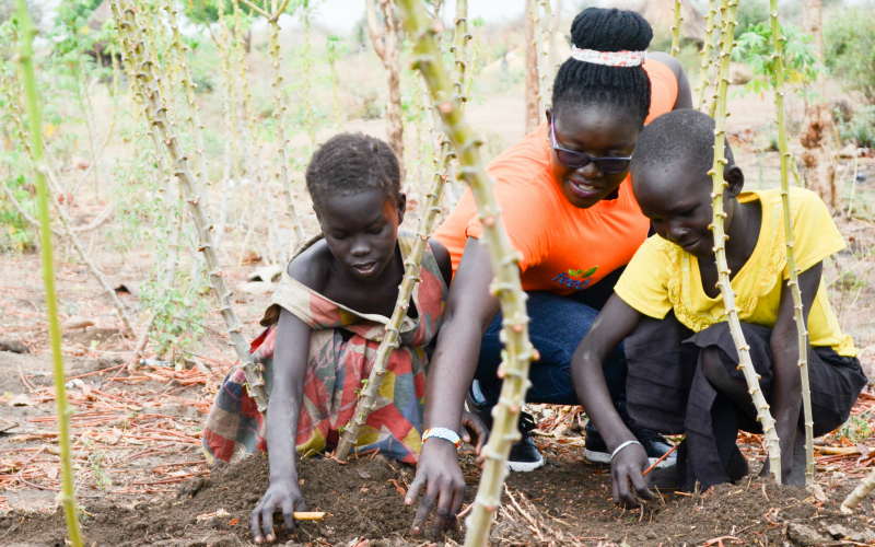 Sunday and two children work in a field in South Sudan