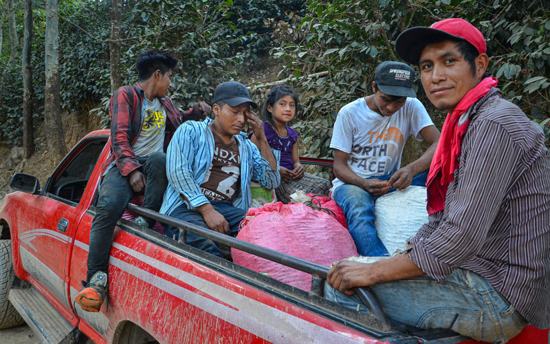 a group of children and youth sit in the back of a red pickup truck