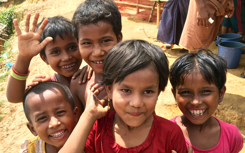 A group of Rohingya children smiling and waving