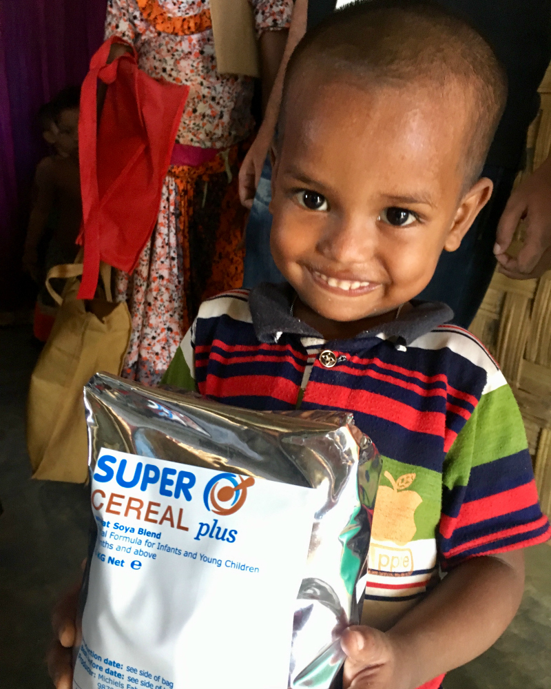 A little Rohingya boy with food aid