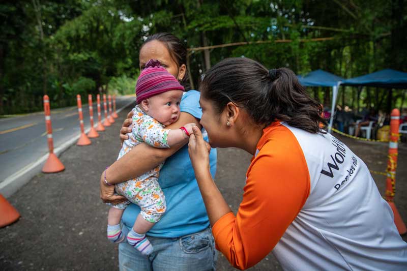 A World Vision staff member plays with a baby at the Colombia/Venezuela border.