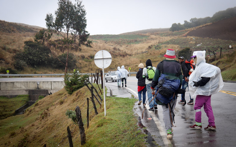 A group of Venezuelan migrants travel along a mountain road in the rain.