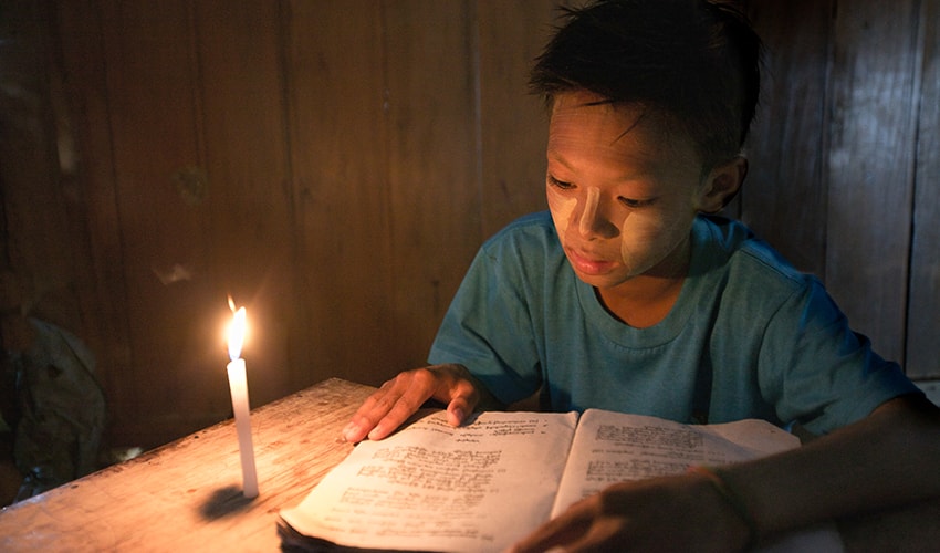 A boy studies by candlelight in Myanmar.