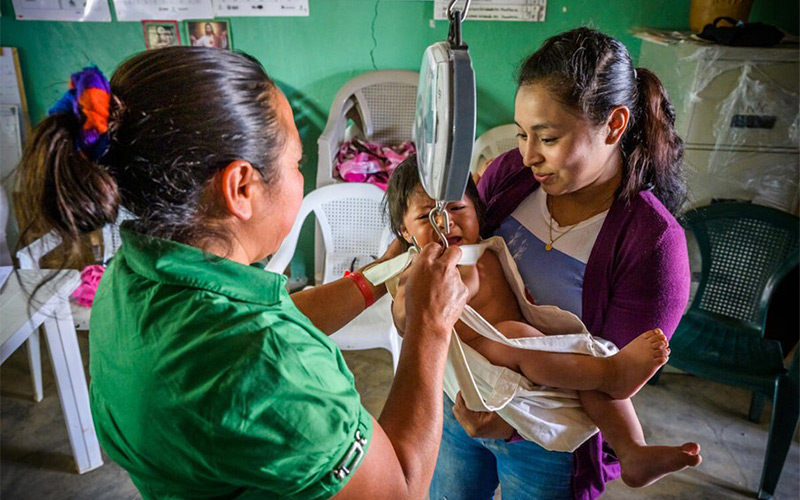 A healthcare worker weighs a baby at a health center.