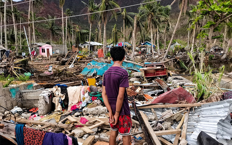 A boy looks at the debris from destroyed houses.