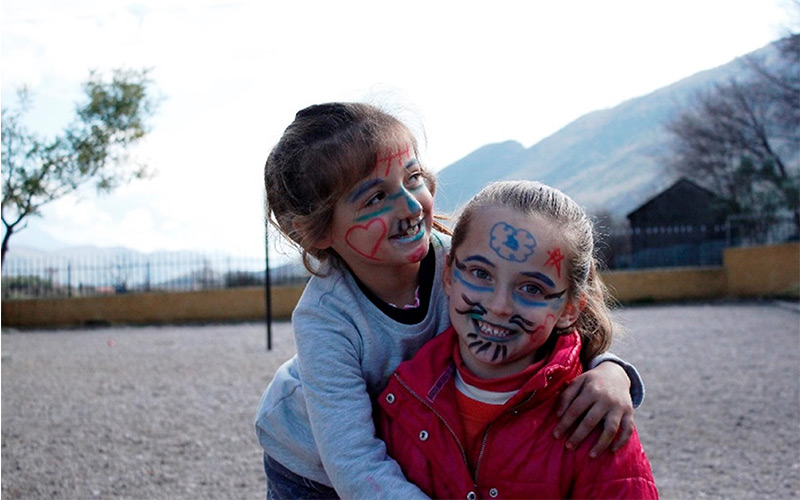 two girls with face paint embrace each other.