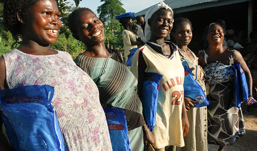 A group of moms stand in a line holding new mosquito nets that will protect them and their babies from malaria and other mosquito-borne illnesses.