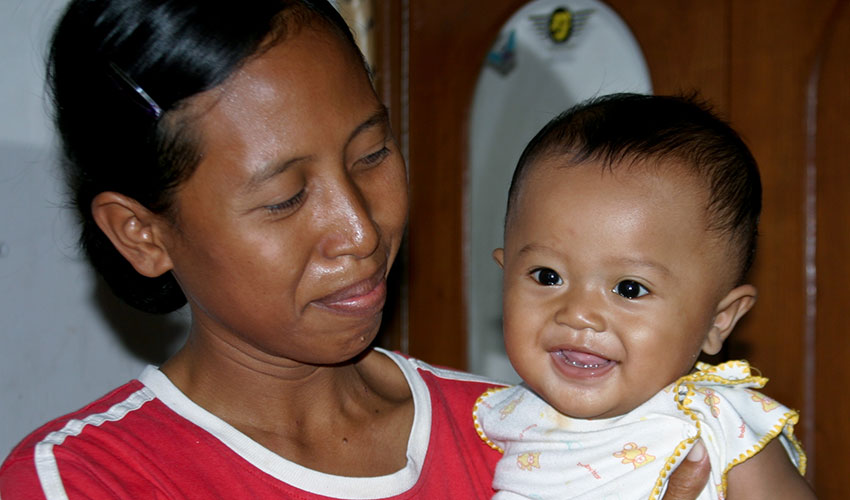 In Indonesia, a mother holds her infant son in her arms and looks into his face, lovingly.